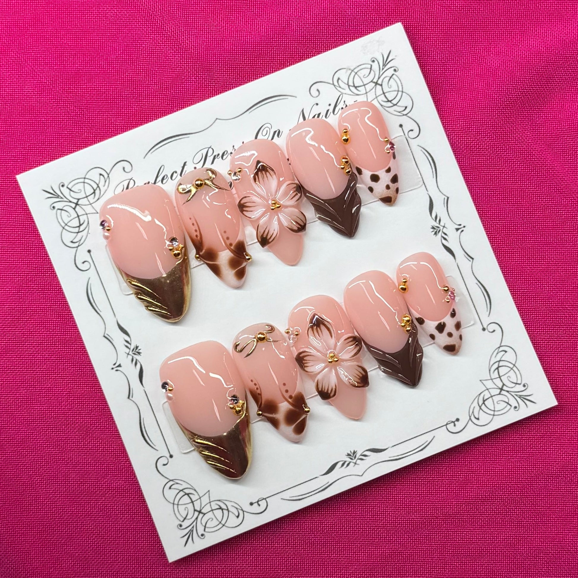 A set of 10 false press-on nails displayed on a white decorative card, featuring a pink and white ice cream cone design with chocolate drizzle and white chocolate flowers, set against a bright pink fabric background.